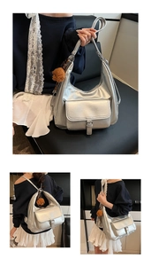 Detail of silver metallic tote bag with buckle pocket and brown teddy bear charm