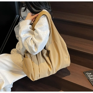 Detail view of khaki canvas tote bag with pleated design and wide strap on steps