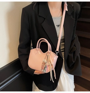 Detalle del bolso tipo cubo en cuero rosa con colgante de oso y borla en una modelo