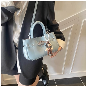 Detail van lichtblauwe emmertas met zilveren draaisluiting en schattige tasaccessoire