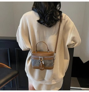 Détail d'un sac boîte structuré avec cuir marron et coutures contrastées en tissu gris