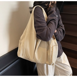 Detail view of large canvas tote bag showing side pocket and soft cream fabric texture
