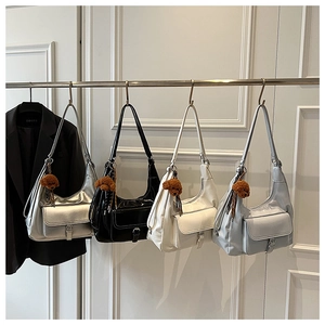 Detail of hobo shoulder bags in silver, black, cream, and blue with plush bear charms