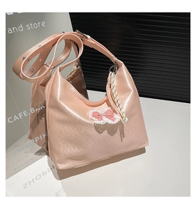 Macro shot of pink glossy crescent tote bag with lace bow and silver metal buckle