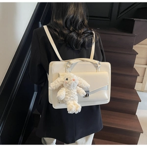 Detail of cream glossy patent leather backpack with cute white plush bunny charm