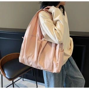 Lifestyle shot of a large pink nylon tote bag with functional pockets worn by a model