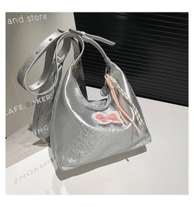 Close-up of silver metallic tote bag with pink lace bow and colorful braided charm