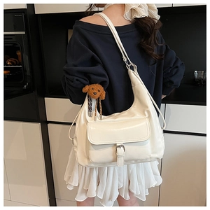 Detail of cream white faux leather tote bag with pocket and plush teddy charm