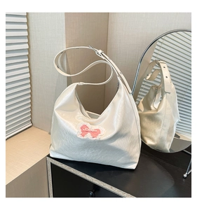 Detail view of white hobo bag featuring pink lace bow and pearl accents on PU leather