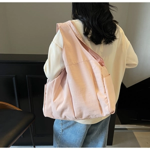 Macro detail of large pink canvas tote bag showing wide shoulder strap and side pocket