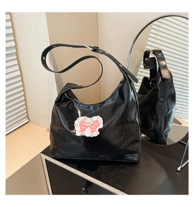 Detail of black semi-circle hobo bag featuring pink bows and white lace decorations