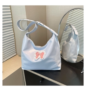 Detail of light blue tote bag featuring pink bow and white lace trim on wooden surface