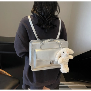 Silver backpack on model showing minimalist rectangular design and plush bunny charm