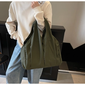 Macro detail of army green canvas tote bag showing side pocket and durable fabric texture