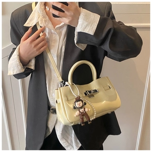 Detail van beige emmertas van oliewasleder met zilveren gesp en parelhanger