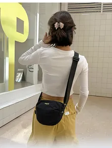 Detailed back view of a minimalist black crossbody bag with adjustable wide strap on a model