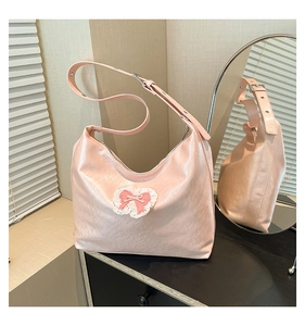Detailed view of pink hobo bag with delicate lace embroidery and pearl bow accent