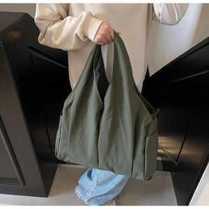 Macro detail of olive green nylon tote bag featuring side pockets and matte texture