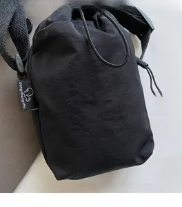Detail of black nylon drawstring crossbody bag with adjustable strap and logo embroidery
