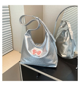 Detail of silver metallic tote bag with pleated texture and pink bow on lace base