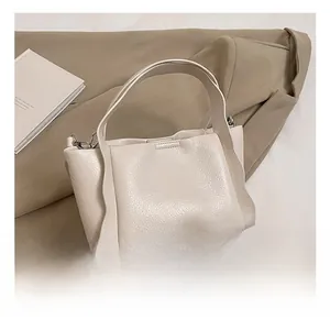 Detail showing creamy lychee texture leather bucket bag with brand logo and gold hardware