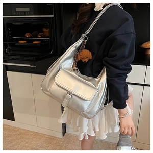 Detail of silver metallic hobo tote bag with a cute brown plush dog charm and pocket
