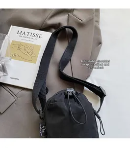 Detail showing adjustable woven shoulder strap and nylon drawstring on sporty crossbody bag