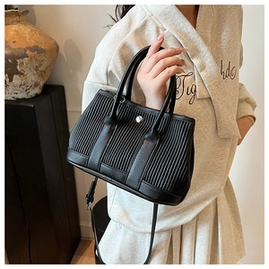 Detail of black pleated bucket bag with silver metal ring and smooth leather strap