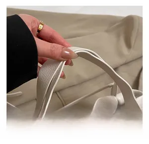 Close-up of the cream-white pebbled leather handbag with reinforced handle and gold hardware