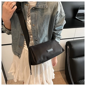 Détail d'un sac bandoulière en nylon noir porté par un mannequin pour style décontracté