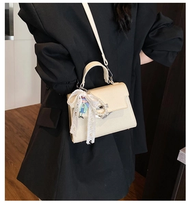 Détail du sac beige grainé avec nœud en dentelle, perles et fermoir rotatif en argent