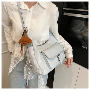 Blue-grey oversized crescent tote bag featuring a cute brown puppy plush charm on the strap