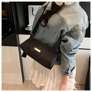 Détail du sac polochon en nylon noir avec logo métallique et large bandoulière