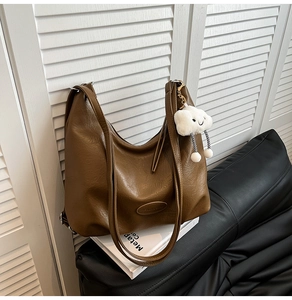 Détail du sac Hobo en cuir marron souple avec un pendentif en peluche nuage blanc