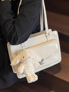 Minimalist cream white shoulder bag with silver buckle and plush bunny charm on model