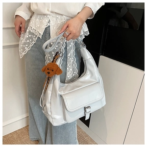 Detail of white hobo tote bag featuring a glossy finish and a cute brown poodle plush charm