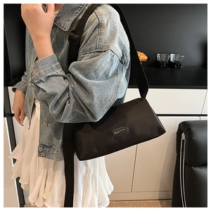 Vue détaillée du sac polochon en nylon noir avec écusson logo et large bandoulière griffée