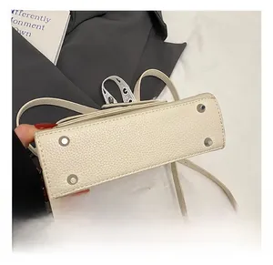 Détail du fond d'un sac en cuir blanc à grain avec quatre pieds de protection en métal