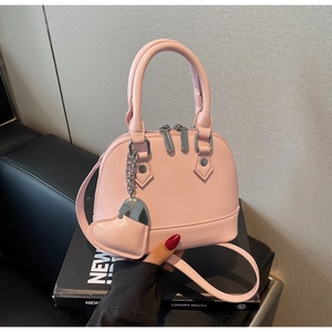 Detail of light pink shell crossbody bag with silver heart pendant and metal zippers
