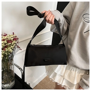 Détail du sac polochon en nylon noir montrant la bandoulière large et le logo