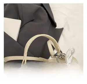 Détail de la poignée en cuir grainé du sac avec nœud en dentelle et pendentif chic