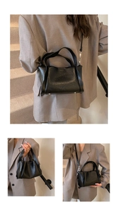 Detail of black lychee texture bucket bag with silver bottom studs and adjustable strap