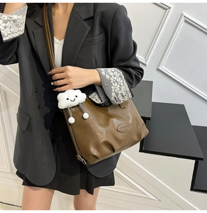 Détail d'un sac bandoulière marron avec un charme nuage en peluche blanc et des volants