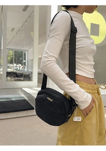 Detailed view of black nylon crossbody bag with adjustable strap and brand logo