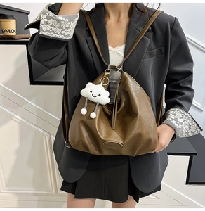 Détail d'un sac cabas en cuir marron souple avec un charmant nuage en peluche et logo