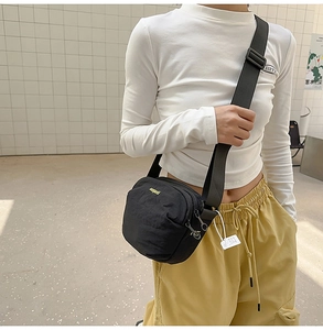 Detail of black nylon crossbody bag featuring yellow embroidered logo and wide strap