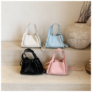 Litchi texture handbags in four colors displayed on stone steps with ruffled wing detail