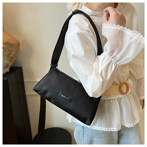 Détail du sac bandoulière en nylon noir avec sangle réglable et écusson de logo frontal
