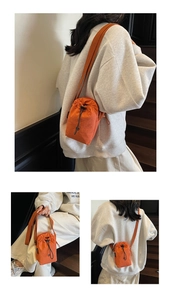 Detail view of mini orange nylon crossbody bucket bag with drawstring and thin strap