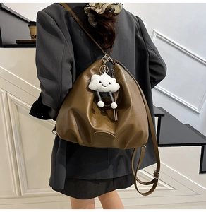 Détail du sac demi-lune en similicuir marron olive avec bandoulière et breloque en peluche